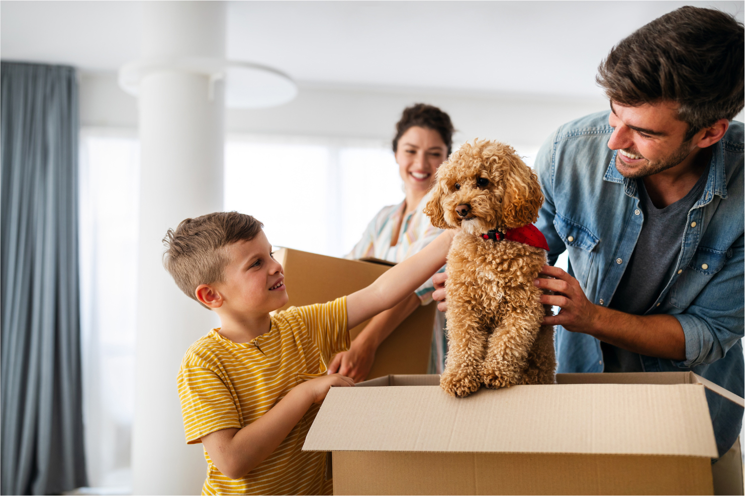 Smiling Family Carrying Boxes Into New Home On Moving Day